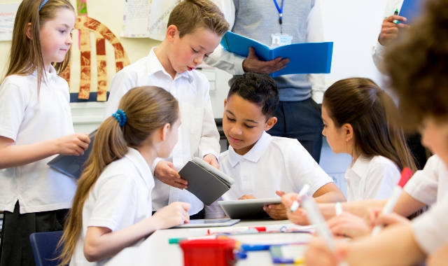 Kids sitting around a table in school uniforms.
